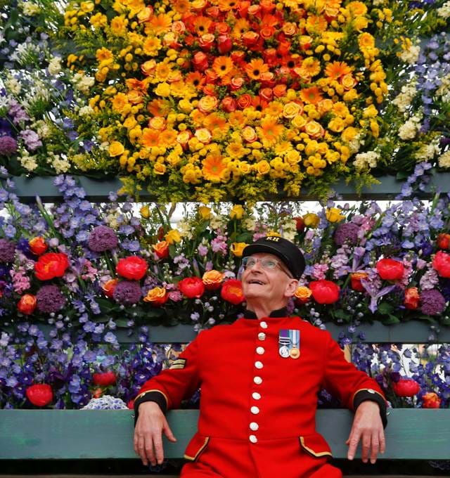 Man with background of flowers at the Chelsea Flower Show in London