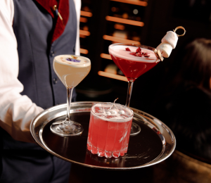 Bartender Holding a Tray with three different festive cocktail drinks